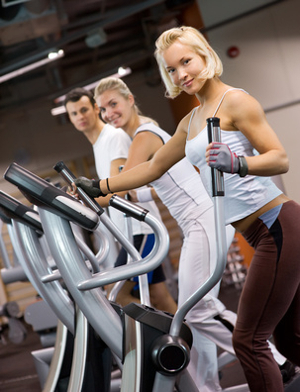 Gelenkschonendes Ausdauertraining auf dem Crosstrainer Drei Menschen trainieren gemeinsam auf Crosstrainern im Fitnessstudio Arabellapark in München Bogenhausen